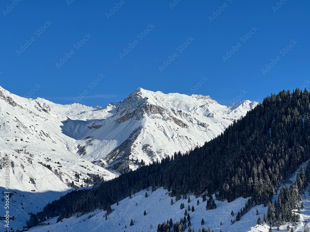 Obraz premium Beautiful sunlit and snow-capped alpine peaks above the Swiss village and winter resort of St. Antönien (St. Antoenien) - Canton of Grisons, Switzerland (Kanton Graubünden, Schweiz)