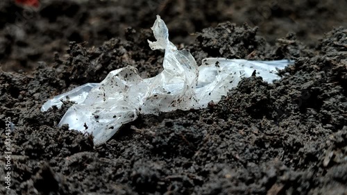 Plastic waste buried in the soil. Plastic pollution is extremely damaging, reducing soil fertility by inhibiting water and air absorption, and poisoning vital organisms like earthworms and microbes.