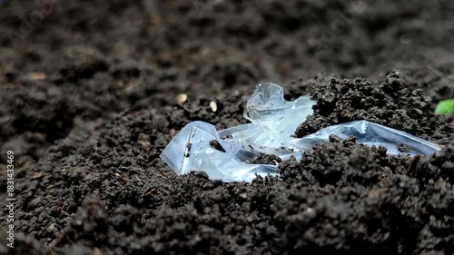 Plastic waste buried in the soil. Plastic pollution is extremely damaging, reducing soil fertility by inhibiting water and air absorption, and poisoning vital organisms like earthworms and microbes.