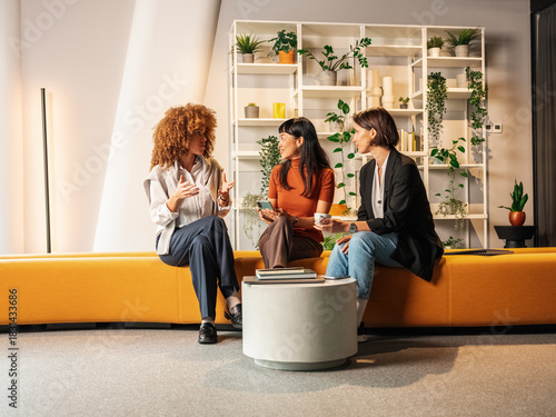 Collaborative Office Conversation Among Three Women in Modern Lounge