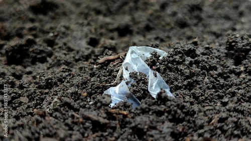 Plastic waste buried in the soil. Plastic pollution is extremely damaging, reducing soil fertility by inhibiting water and air absorption, and poisoning vital organisms like earthworms and microbes.