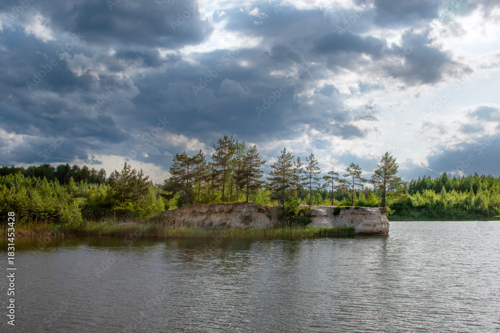 Obraz premium Serene landscape featuring a tranquil lake surrounded by lush greenery and scattered clouds above