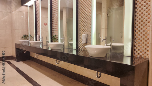 Contemporary interior of public toilet, modern and clean public toilet sink area equipped with large mirror