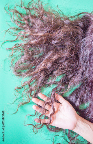 Close up of woman's long brown hair on a green background.