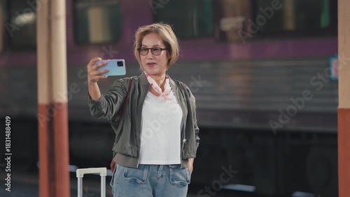 A mature woman with a suitcase travels joyfully at a train station