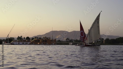 Traditional felucca and modern cruise ship on Nile River near Luxor, Egypt.