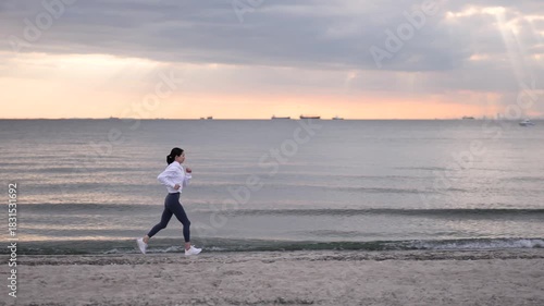 夕方の海岸でジョギングする女性のスローモーショントラッキングショット