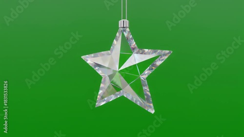 Transparent faceted star ornament hanging on solid green background, sparkling and elegant.