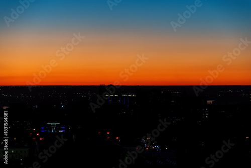 Dramatic sunset over the city skyline, silhouetting the buildings against a vibrant gradient sky