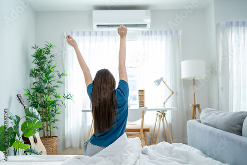 Rear view of young woman getting up from sleep on bed in the morning. 