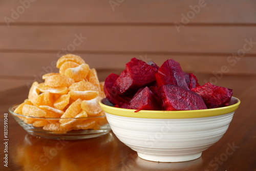 Beetroot chips and tangerines in a bowl on wooden table
