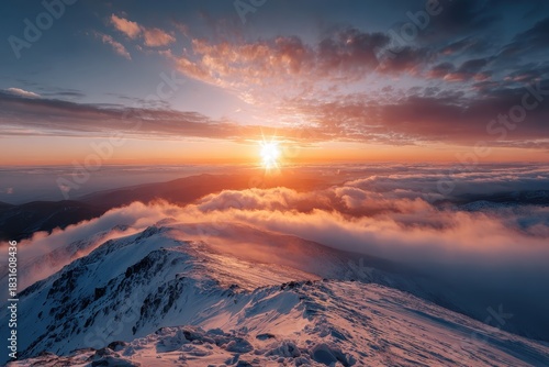 Colorful golden sun rising over snowy mountain peaks during winter, casting warm light across the landscape and illuminating clouds in the early morning atmosphere