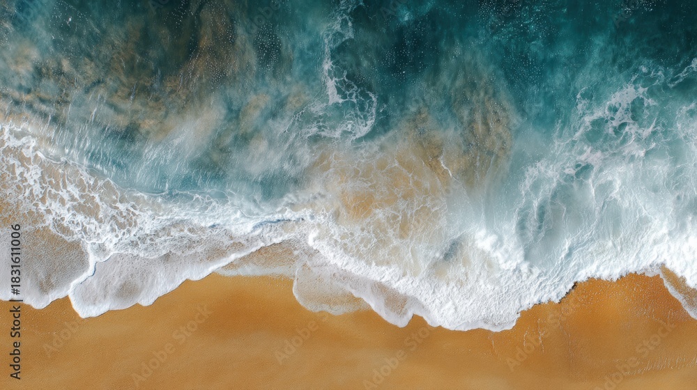 Fototapeta premium Aerial view of a beach with waves crashing onto the sand. the water is a beautiful shade of blue and green, with white foam and spray visible on the surface.