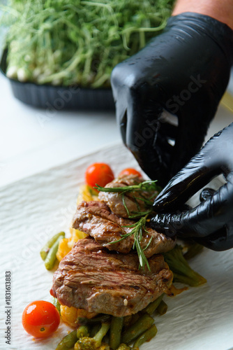 chef prepares beef medallions with vegetables in sauce