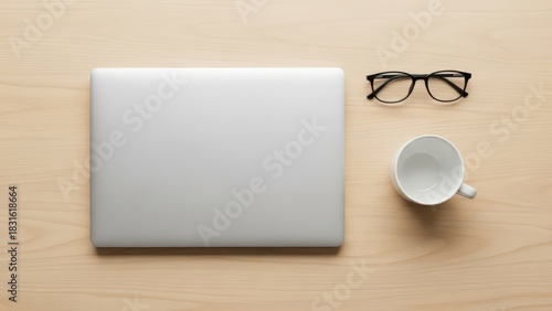 Minimalist workspace with laptop, eyeglasses, and coffee cup on wooden desk