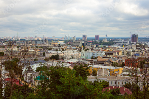 View from Andriyivskyi Descent of Kyiv’s Podil with Kontraktova Square Wheel, Greenery, Historic Rooftops, and Left-Bank High-Rises