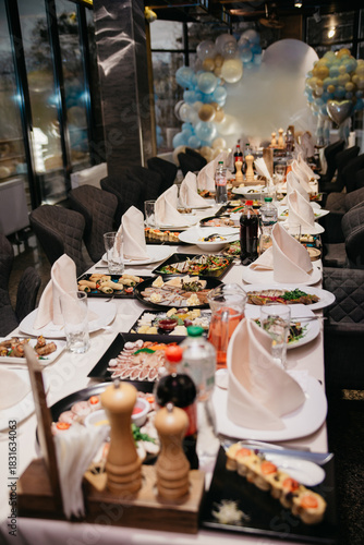 In the restaurant, before the holiday begins, plates, napkins, cutlery and food are placed on tables covered with tablecloths.