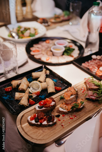 In a restaurant, plates, napkins, cutlery and food are placed on tables covered with tablecloths.