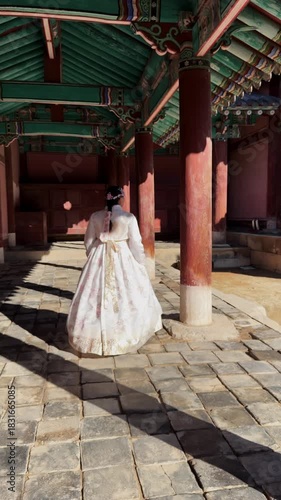 Young korean woman gracefully walking in a historic temple wearing a traditional white hanbok with pink floral embroidery in Seoul
