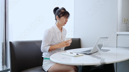 Young asian female entrepreneur enjoying a cup of coffee while sitting in a cafe working on laptop