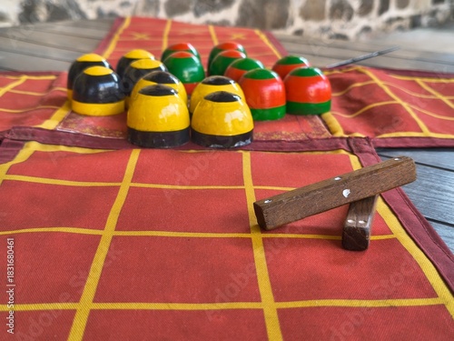 Traditional Indian board game display with colorful wooden pieces on a patterned cloth, reflecting cultural craftsmanship, nostalgia, and classic leisure play rooted in heritage and storytelling.