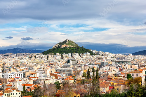 Fototapeta Naklejka Na Ścianę i Meble -  View of Lycabettus mount from Acropolis hill in Athens, Greece. Cityscape of historical town of Athens with old and modern Greek houses against dramatic sky.