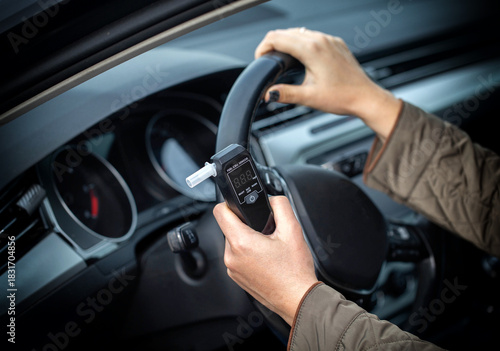 Female Driver Holding Breathalyzer And Steering Wheel. Deciding About Safe Driving After Test.