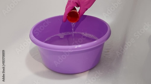 Purple basin with glove stirring dilute detergent in bright clean environment