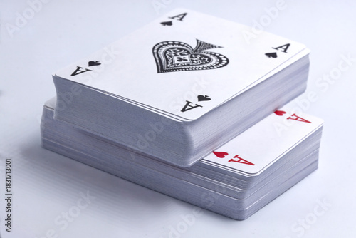 Two decks of playing cards stacked on a white background, with the Ace of Hearts and the Ace of Spades on top.
