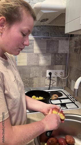 A young woman peeling potatoes in the kitchen