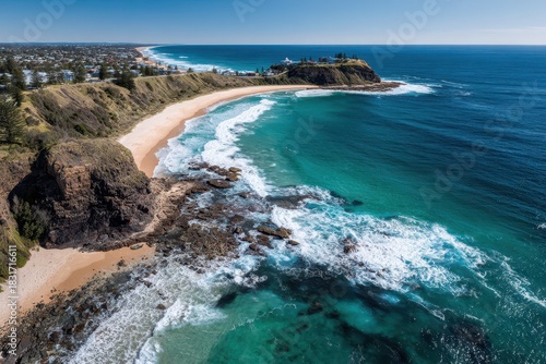Drone photograph of Nobbys Beach coast in Newcastle, capturing turquoise water, waves and coastal headland in bright light