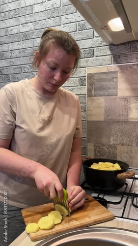 A young woman cuts potatoes into slices