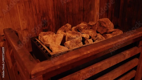 sauna stones, spa ritual, healing heat. Detail view of heated sauna stones resting on metal stove inside wooden sauna, used to generate therapeutic dry heat.