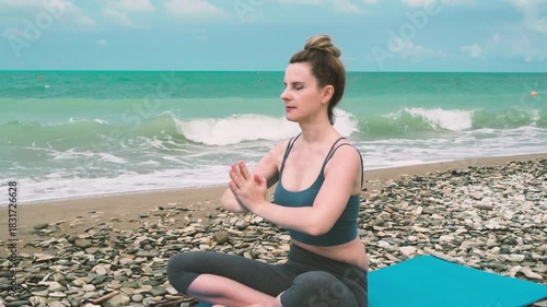Female Traveler Meditating on a Beach by the Sea in the Lotus Position. Meditation, Concentration, Relaxation, Yoga, Healthy Lifestyle.