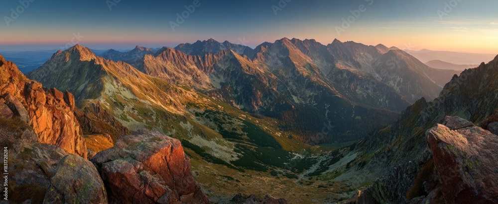 Obraz premium Rugged mountain range illuminated by warm sunrise or sunset light.