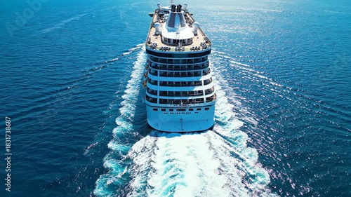 Large passenger vessel sailing on deep blue ocean water creating white wake