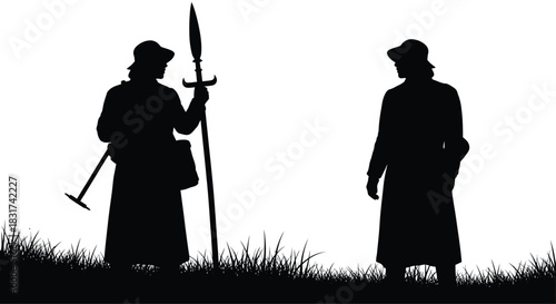 Silhouette of two historical soldiers standing on a grassy hill against a bright dramatic sky
