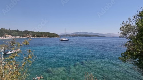 Panoramic view of turquoise cove with anchored boats and lush greenery