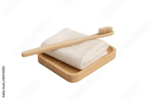 Bamboo toothbrush rests on folded white towel in wooden tray