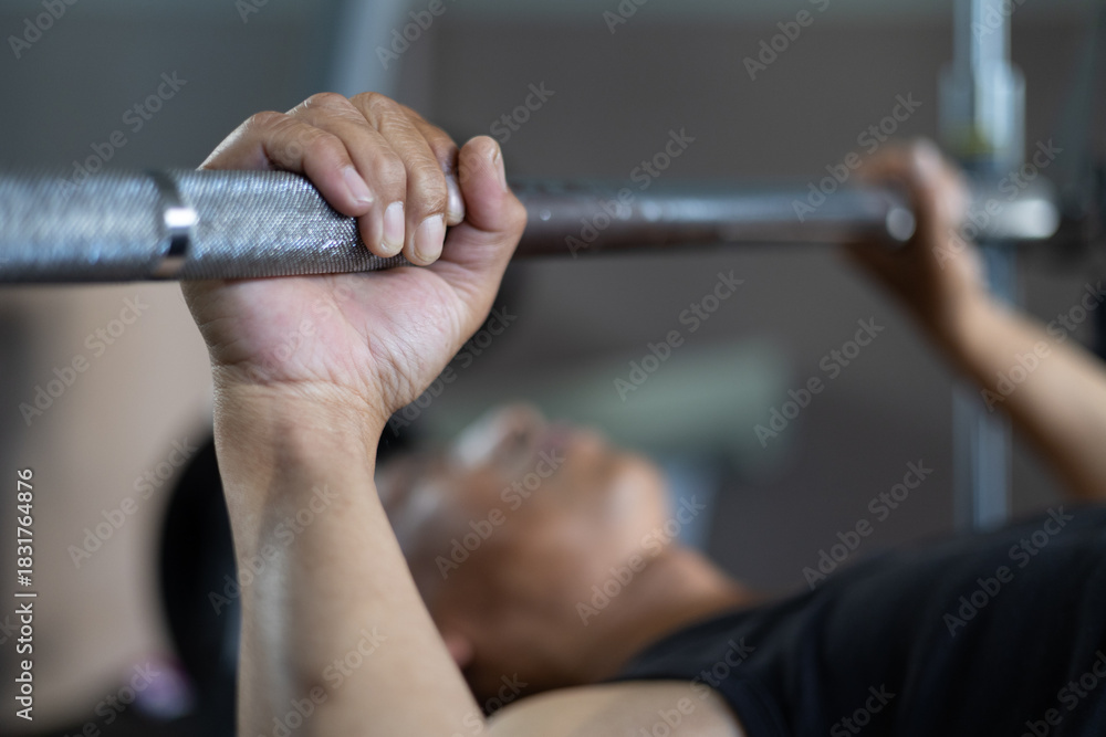 Obraz premium Close-up of a man’s hand gripping a barbell during bench press workout in the gym, control focused muscle training in a fitness lifestyle.
