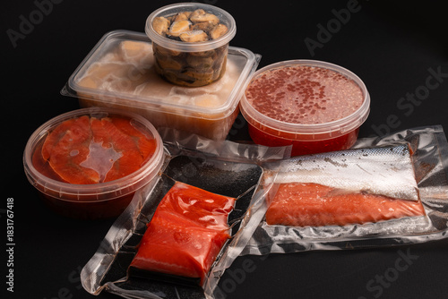 Assorted Seafood Products in Plastic and Vacuum Packaging on Dark Background