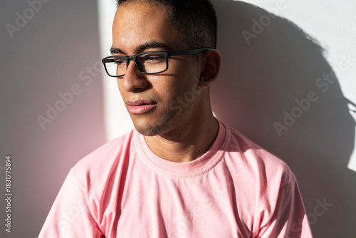 Latino man in warm sunlight observing quiet moment with ease