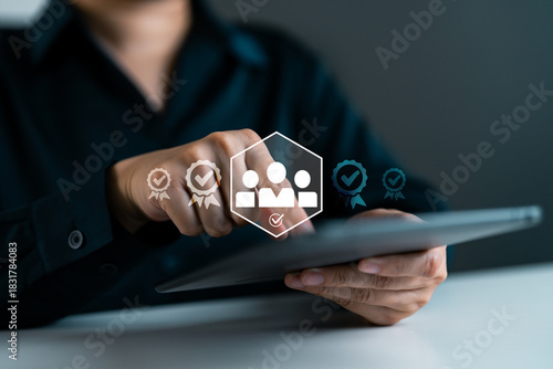 Business person using digital tablet with virtual icons of certified team and checkmarks, employee verification, HR approval process, team qualification and digital credential validation.