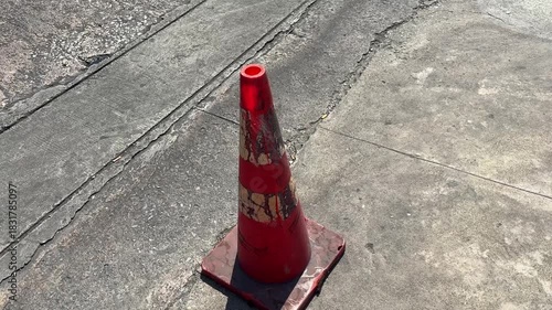 Old orange traffic cone on cement road sunny day outdoor summer day pov shot.