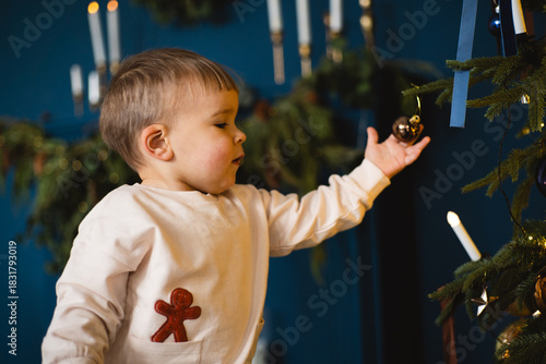 Child enjoys the festive spirit while wearing a gingerbread man outfit near holiday decorations in a cozy home setting