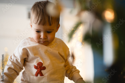 Child enjoys the festive spirit while wearing a gingerbread man outfit near holiday decorations in a cozy home setting