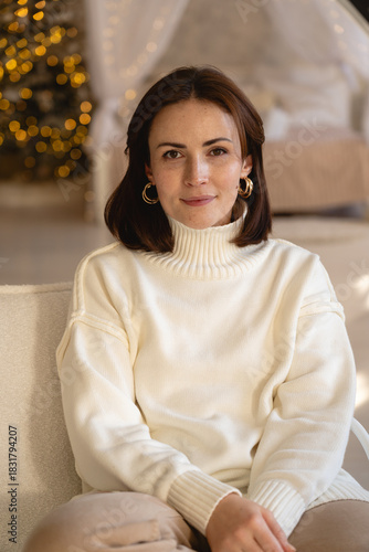 Woman relaxing on a cozy couch in a stylish indoor setting with warm lights during winter
