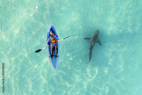 Aerial view of a lone kayaker paddles through the turquoise waters, shadowed by a dark shark lurking nearby, creating a stark contrast of serenity and peril, Hadera, Haifa District, Israel.