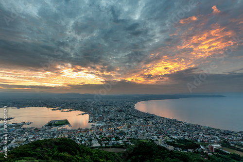 Dramatic sunset clouds and golden light illuminating the iconic cityscape of Hakodate, Hokkaido, viewed from Mount Hakodate.