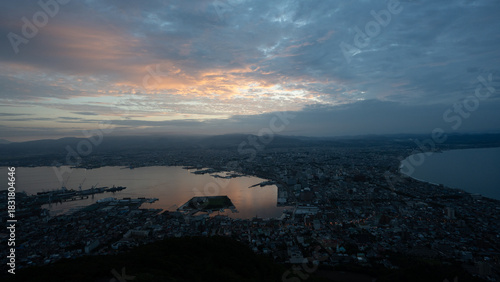 Dramatic sunset clouds and golden light illuminating the iconic cityscape of Hakodate, Hokkaido, viewed from Mount Hakodate.